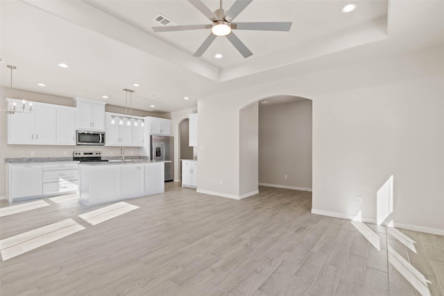 kitchen featuring light hardwood / wood-style flooring, white cabinetry, hanging light fixtures, stainless steel appliances, and an island with sink