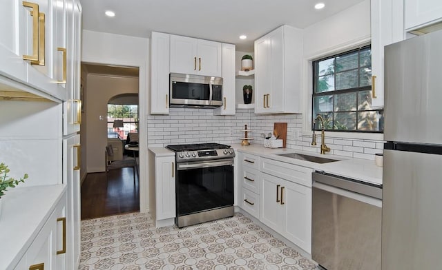 kitchen featuring sink, backsplash, stainless steel appliances, and white cabinets