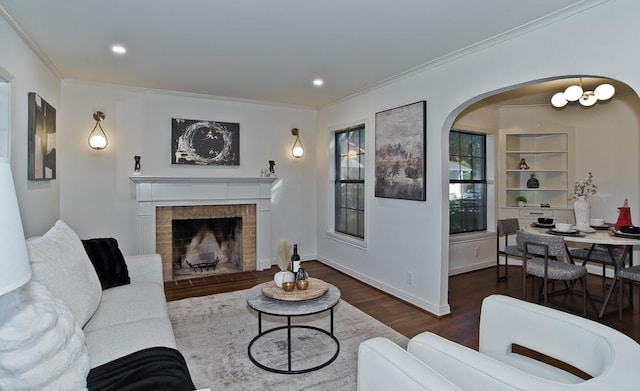 living room with dark hardwood / wood-style flooring, a brick fireplace, and ornamental molding