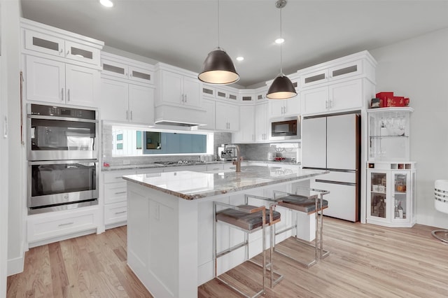 kitchen featuring white cabinets, appliances with stainless steel finishes, a center island, and light wood-type flooring