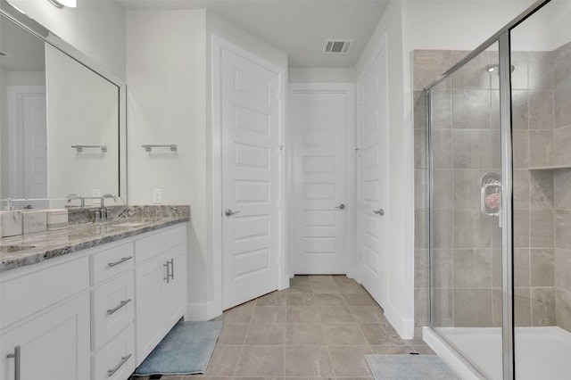 bathroom with a shower with door, vanity, and tile patterned flooring