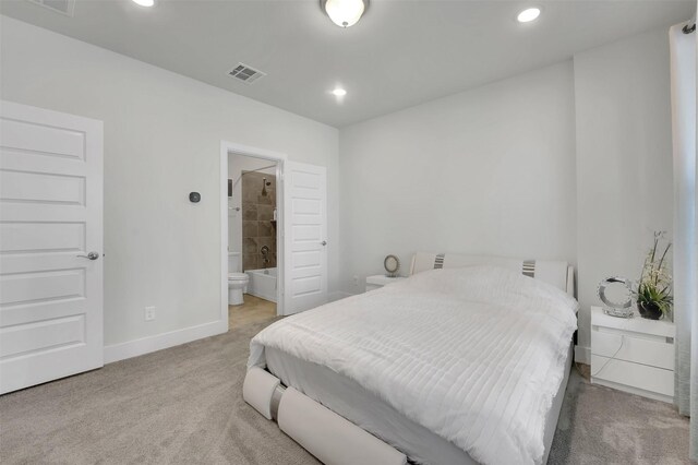 bedroom with connected bathroom and light colored carpet