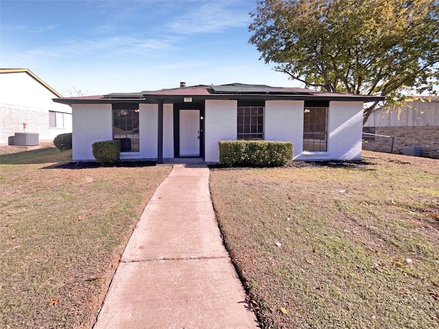 ranch-style house with a front yard and central air condition unit