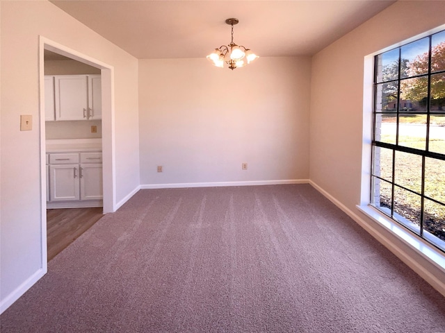 spare room featuring a notable chandelier and carpet floors