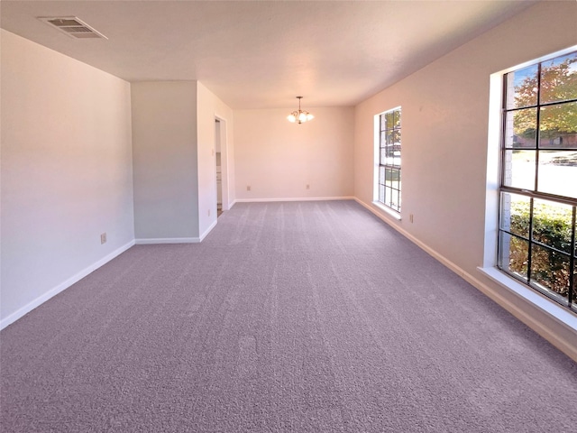 carpeted spare room with a notable chandelier and a healthy amount of sunlight