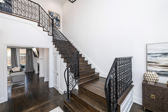 stairs featuring a towering ceiling and wood-type flooring