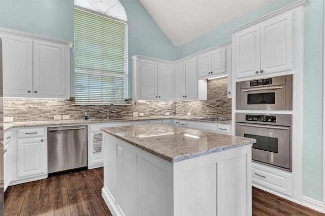 kitchen with sink, white cabinetry, stainless steel appliances, a center island, and light stone counters