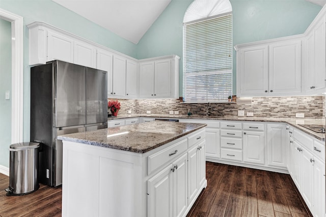 kitchen featuring tasteful backsplash, a kitchen island, dark wood-type flooring, white cabinetry, and stainless steel refrigerator