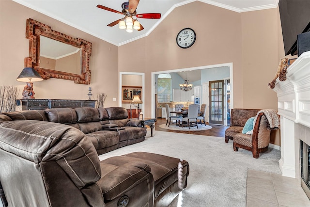 carpeted living room featuring ceiling fan with notable chandelier, crown molding, a fireplace, and high vaulted ceiling