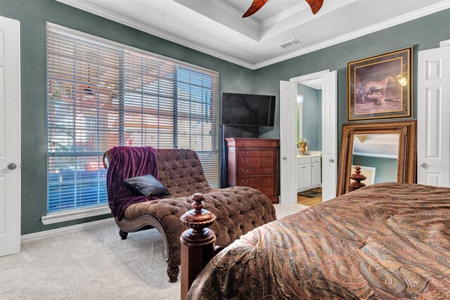 bedroom featuring ornamental molding, light colored carpet, a tray ceiling, ceiling fan, and connected bathroom