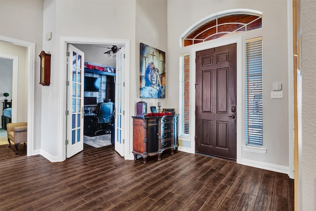 foyer entrance with dark wood-type flooring and a towering ceiling