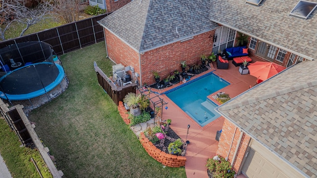 view of pool featuring outdoor lounge area, a patio area, a trampoline, and a lawn