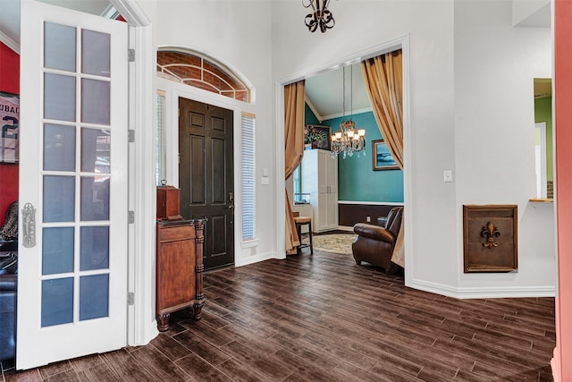 foyer featuring a healthy amount of sunlight, ornamental molding, dark wood-type flooring, and a chandelier