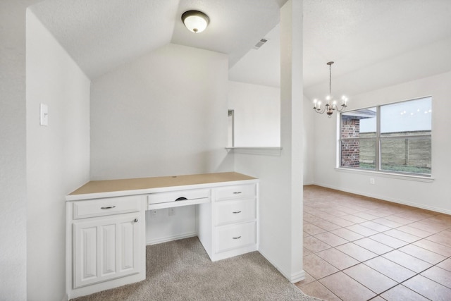 unfurnished office featuring light tile patterned floors, an inviting chandelier, built in desk, a textured ceiling, and vaulted ceiling