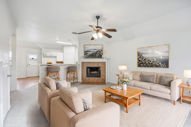 living room featuring ceiling fan and a tiled fireplace