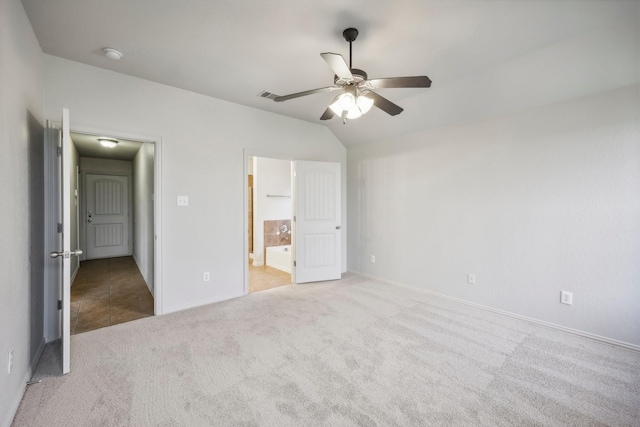 unfurnished bedroom featuring light carpet, vaulted ceiling, ceiling fan, and ensuite bathroom