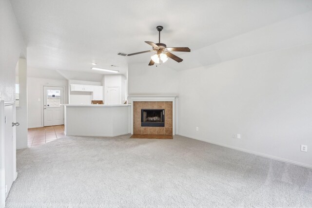 unfurnished living room with ceiling fan, a fireplace, and light colored carpet