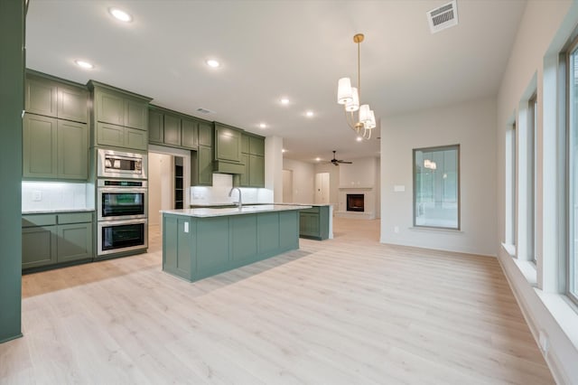 kitchen with pendant lighting, green cabinets, sink, light hardwood / wood-style flooring, and tasteful backsplash