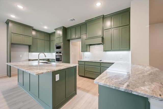 kitchen featuring green cabinets, light stone counters, and stainless steel appliances