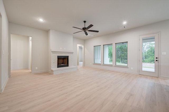 unfurnished living room with ceiling fan, light hardwood / wood-style floors, and a brick fireplace