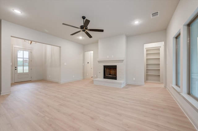 unfurnished living room featuring ceiling fan, light hardwood / wood-style floors, and a brick fireplace