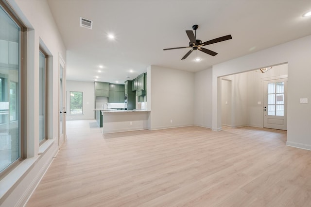 unfurnished living room with a wealth of natural light, ceiling fan, and light wood-type flooring