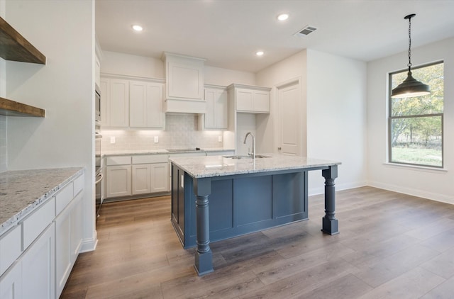 kitchen featuring pendant lighting, sink, light stone countertops, white cabinetry, and stainless steel appliances