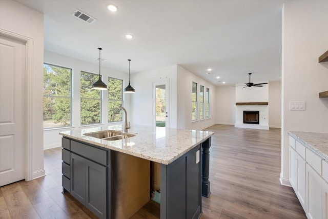 kitchen featuring light stone countertops, white cabinetry, sink, and hanging light fixtures