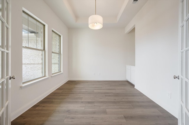 empty room with a tray ceiling, french doors, and hardwood / wood-style flooring