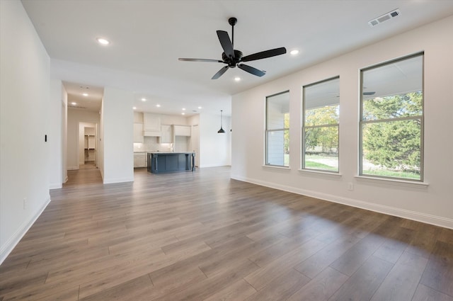 unfurnished living room with ceiling fan and wood-type flooring