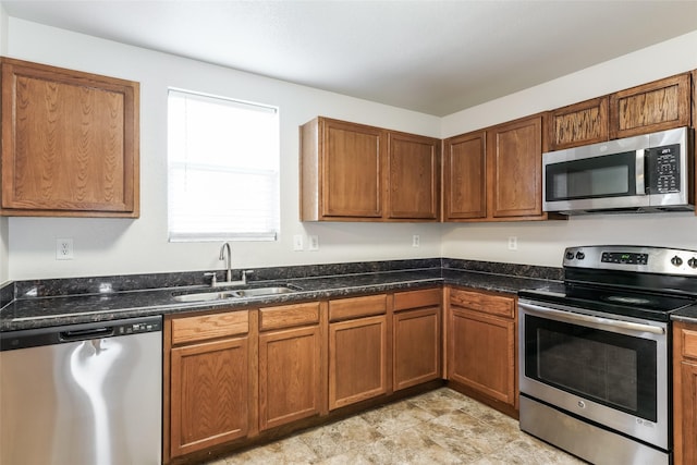 kitchen with sink, appliances with stainless steel finishes, and dark stone counters