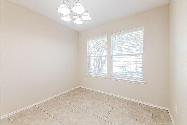 spare room with light tile patterned floors and an inviting chandelier