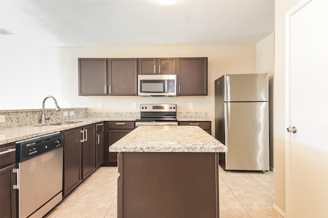 kitchen featuring a kitchen island, sink, stainless steel appliances, light stone countertops, and dark brown cabinets