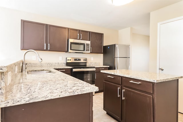 kitchen with dark brown cabinetry, sink, stainless steel appliances, and a kitchen island