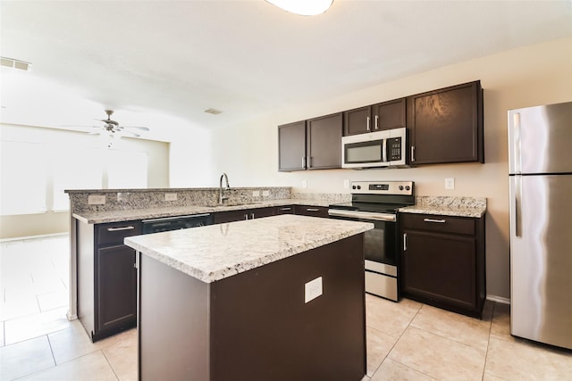 kitchen with stainless steel appliances, light tile patterned flooring, a kitchen island, and sink