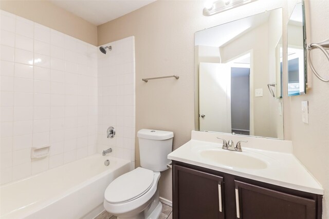full bathroom featuring vanity, tiled shower / bath, and toilet
