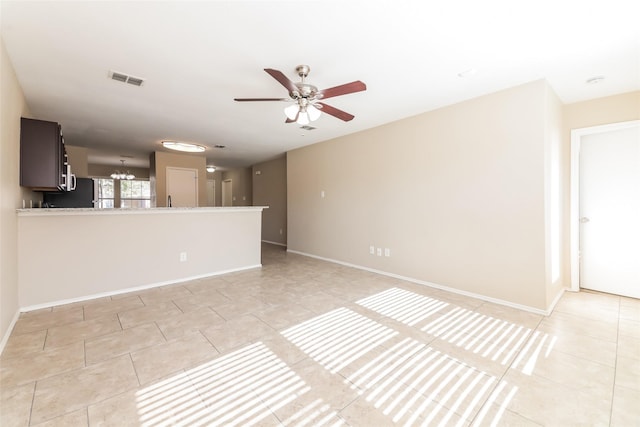 unfurnished living room with light tile patterned flooring and ceiling fan with notable chandelier