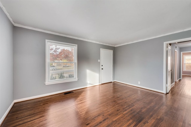 spare room with crown molding, plenty of natural light, and dark wood-type flooring