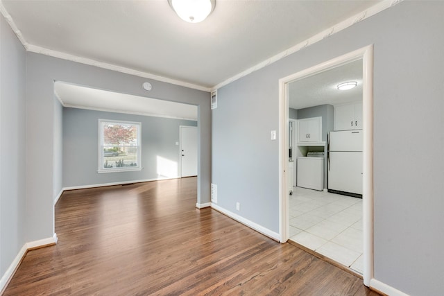 empty room featuring washer / dryer, light hardwood / wood-style floors, and crown molding