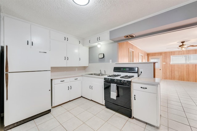 kitchen with kitchen peninsula, black gas range oven, ceiling fan, white refrigerator, and white cabinetry