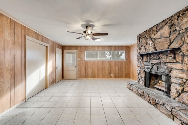 unfurnished living room featuring a fireplace, ceiling fan, and wooden walls