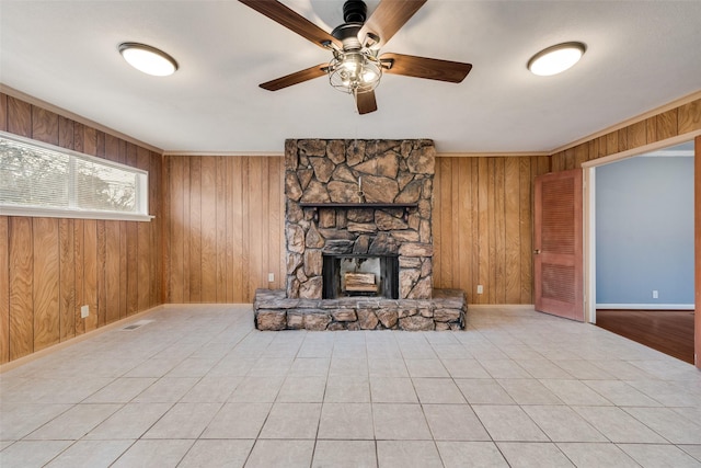 unfurnished living room featuring a fireplace, light tile patterned flooring, ceiling fan, and wood walls