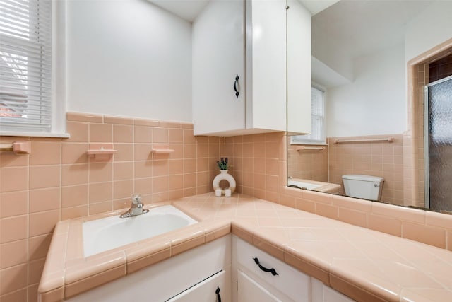 bathroom with vanity, tile walls, and toilet