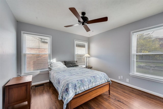 bedroom with multiple windows, dark wood-type flooring, and ceiling fan