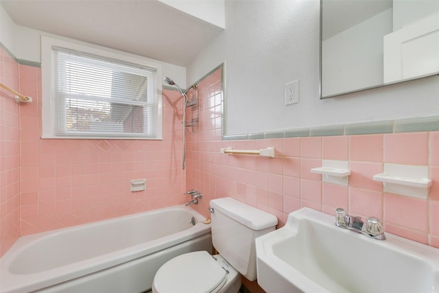 full bathroom with tiled shower / bath combo, toilet, sink, and tile walls