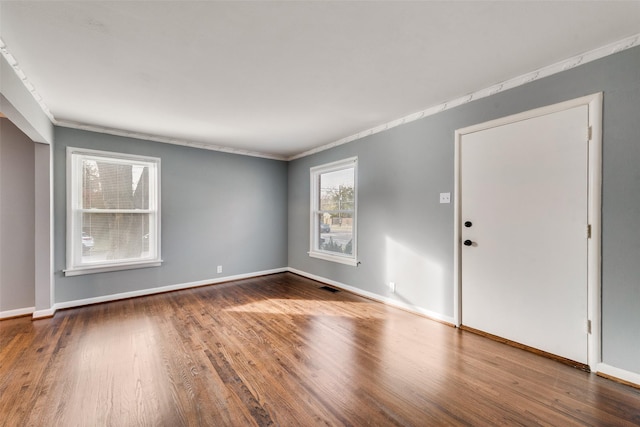 empty room with wood-type flooring and crown molding