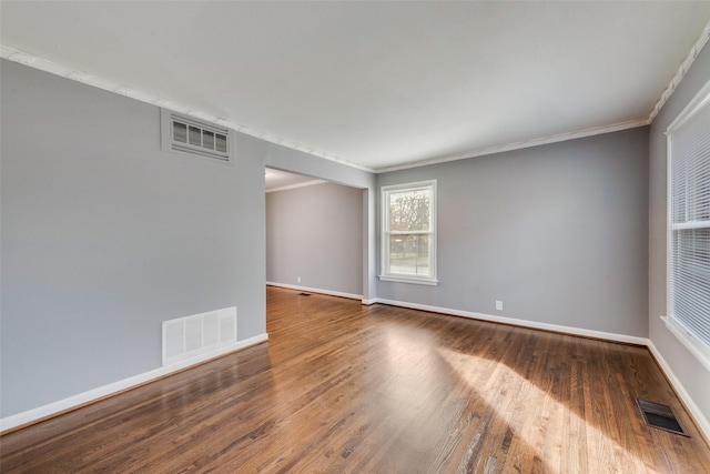 empty room with hardwood / wood-style floors and crown molding