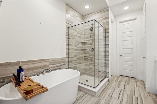 bathroom featuring tile walls and independent shower and bath