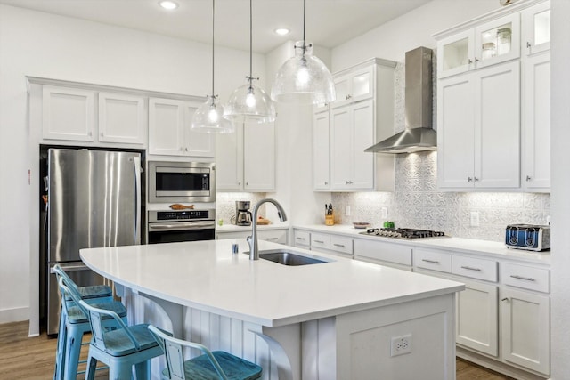 kitchen featuring a center island with sink, wall chimney range hood, sink, and stainless steel appliances