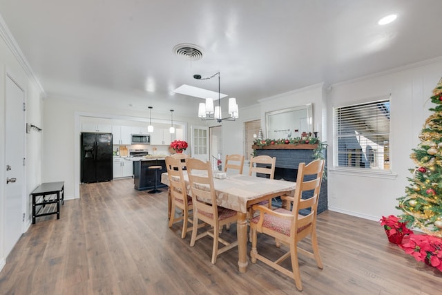 dining space featuring hardwood / wood-style floors, an inviting chandelier, and ornamental molding